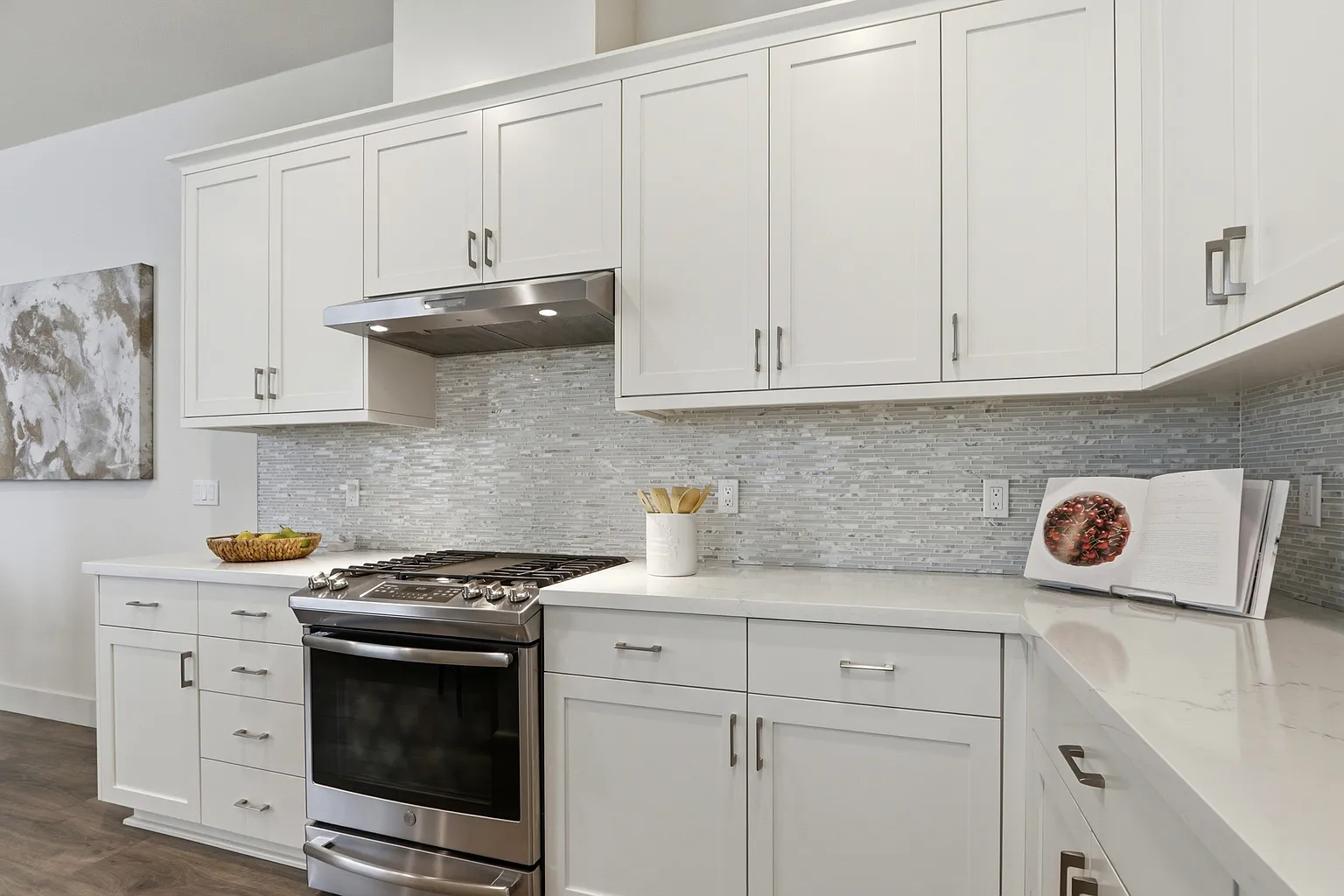 Gas range and stainless hood against marble-look mosaic backsplash