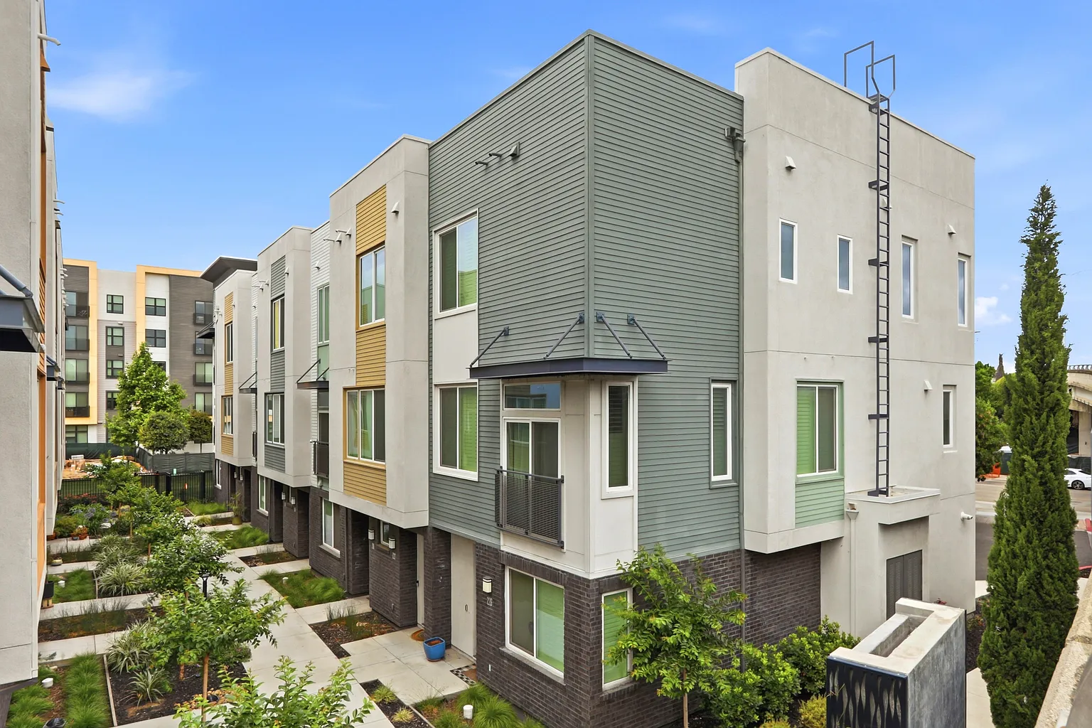 Three-story corner elevation in sage green siding and gray stucco