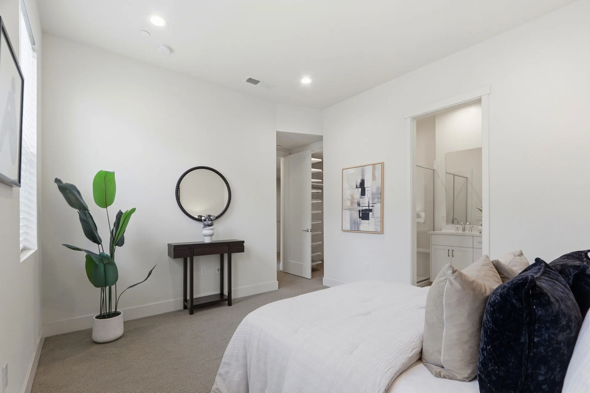 Round mirror over a console table beside the bed