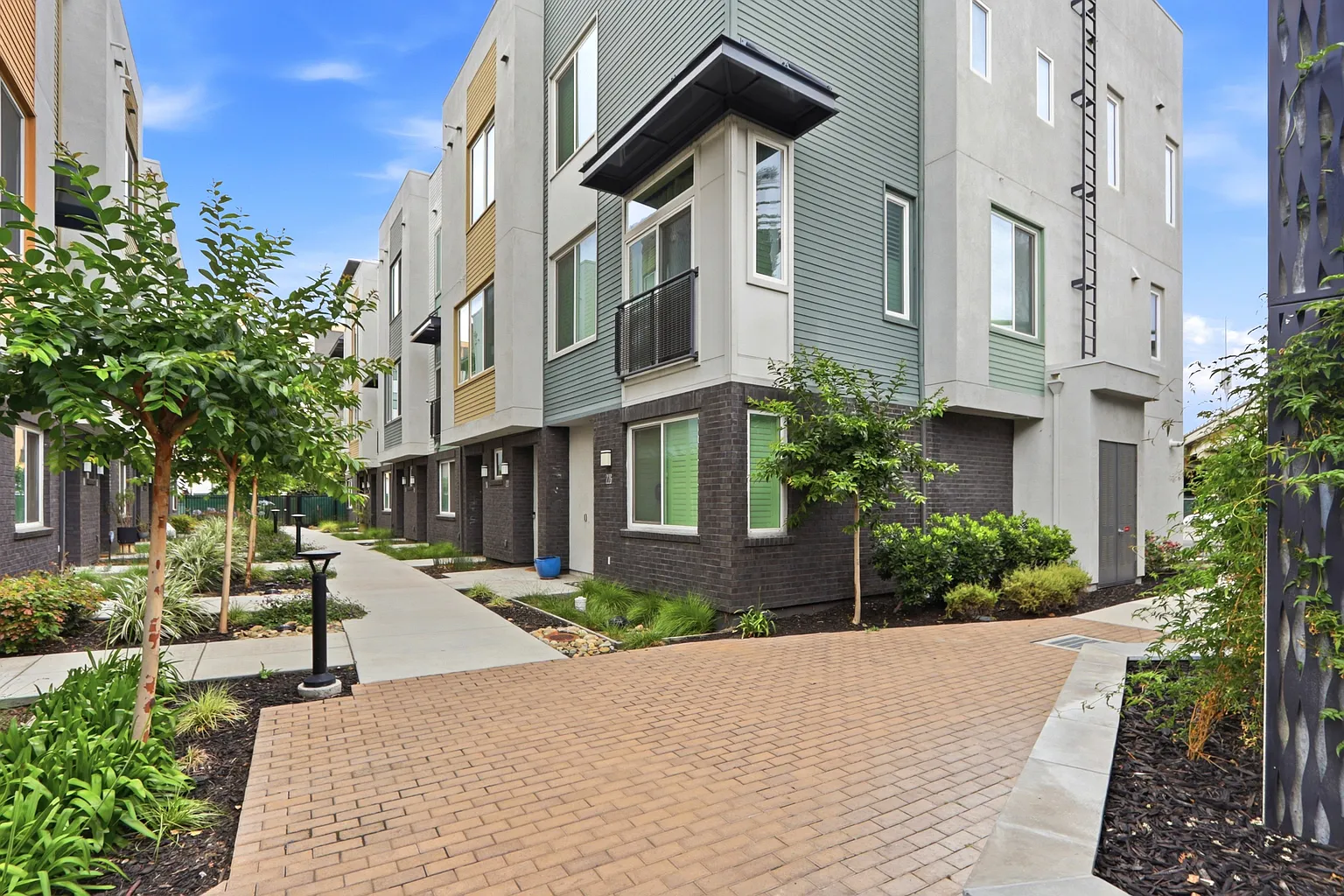 Brick-paved courtyard between townhome rows with young trees