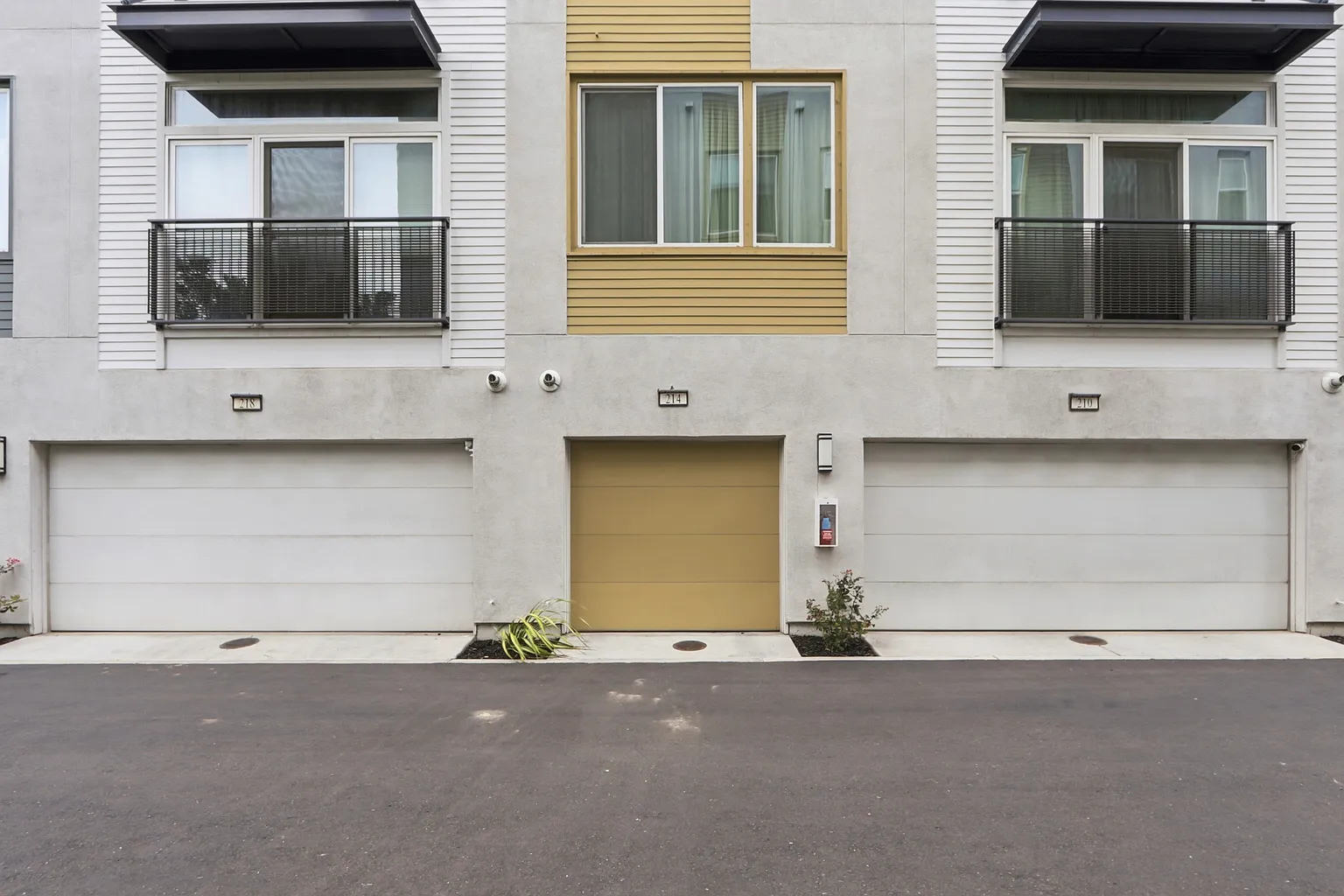 Rear elevation with 214's gold garage door centered between neighbors