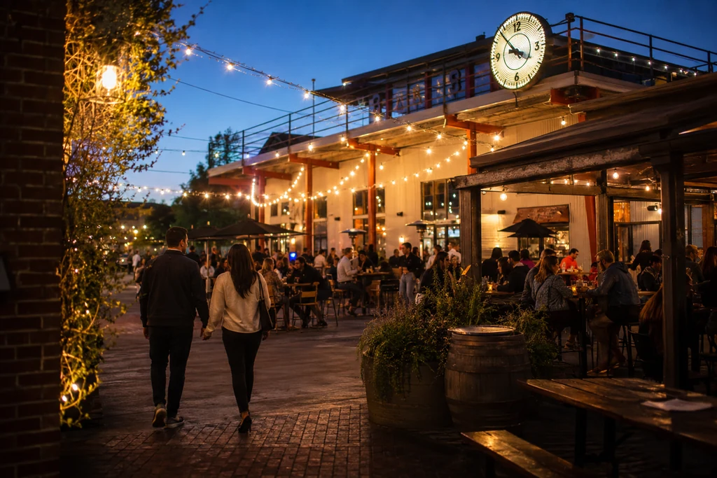 Couple walking into a lively San Pedro Square dining courtyard under string lights at blue hour.